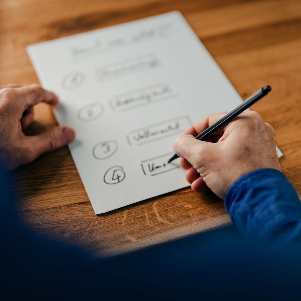 Closeup shot of a businessman writing notes on a white paper on a wooden table Sexual Harassment at the work place