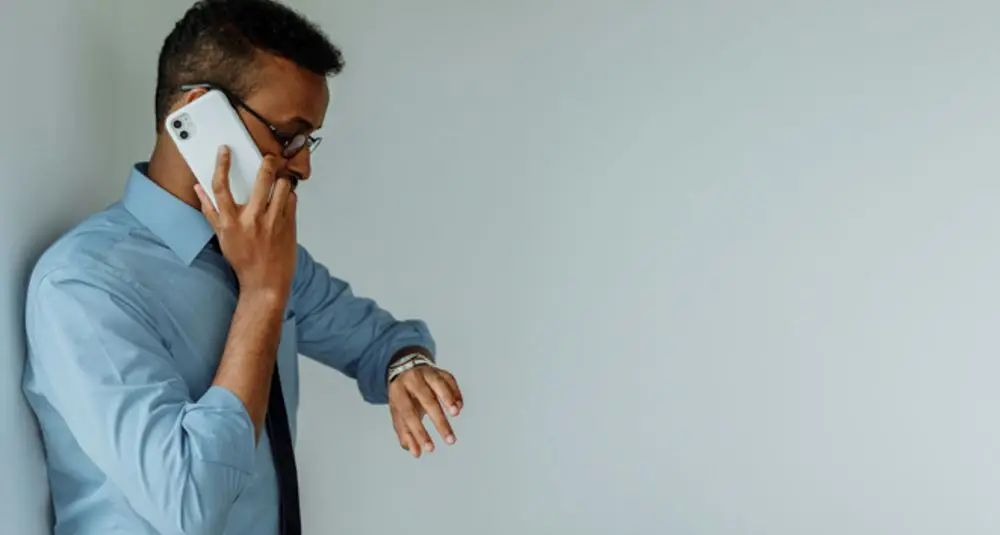 Man checking his watch while discussing normal working hours and overtime in the workplace